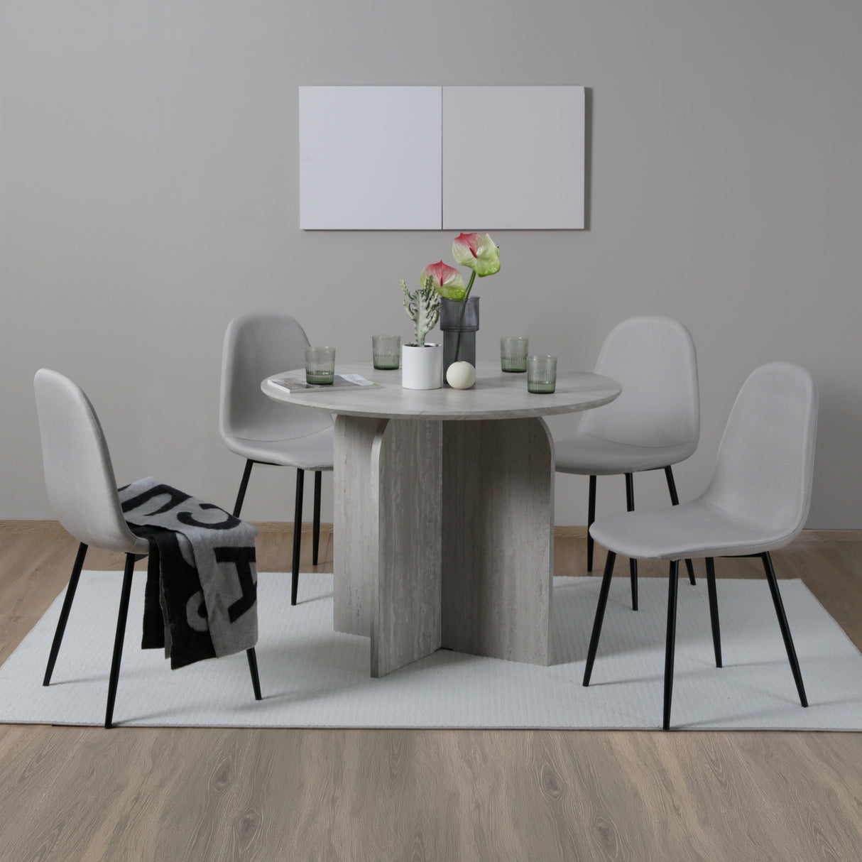Dining room with a round wooden table and four white chairs on a gray rug.