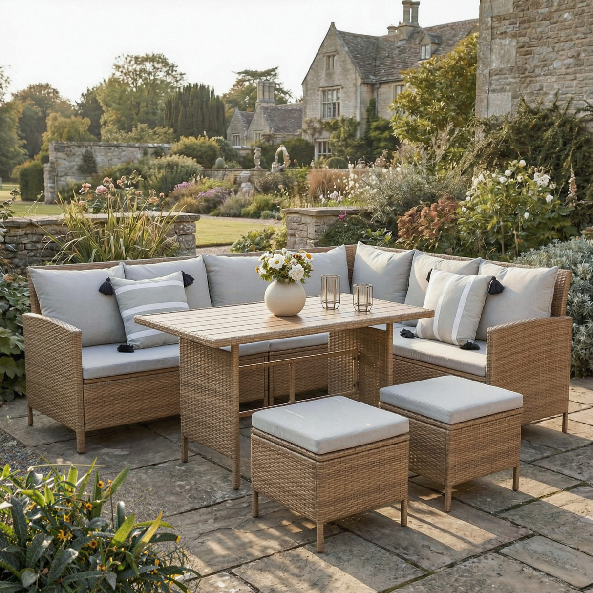 Outdoor patio set with wicker furniture and cushions in a garden setting. Brown with grey cushions