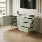 Green Devon Large Sideboard with fluted doors and drawers open, gold handles and legs, displaying tableware beneath a wall mounted TV.