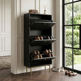 Devon Shoe Cabinet in black with three open tilt out compartments, gold legs and handles, styled with shoes beside a large window.
