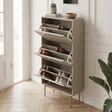 Beige Devon Shoe Cabinet with three open tilt out compartments, gold handles and legs, styled with shoes in a bright hallway.
