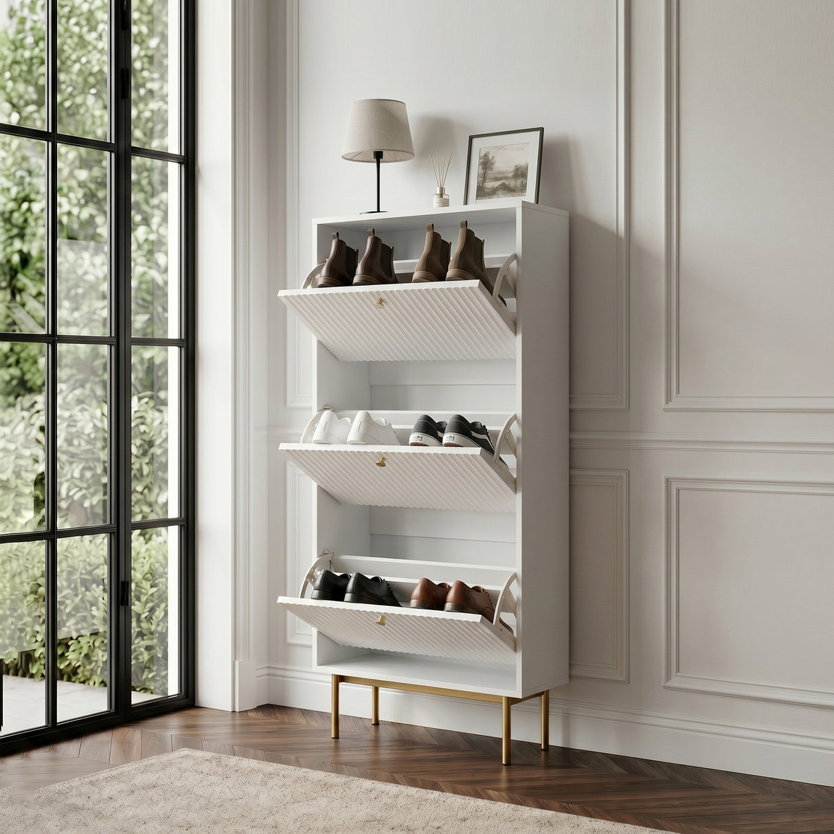 White Devon Shoe Cabinet with three open tilt out compartments, gold handles and legs, styled with shoes in a bright hallway.