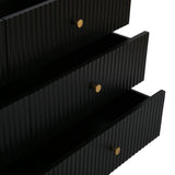 Close up of the black Devon Wide Chest of 6 Drawers showing partially open fluted drawers and gold handles.