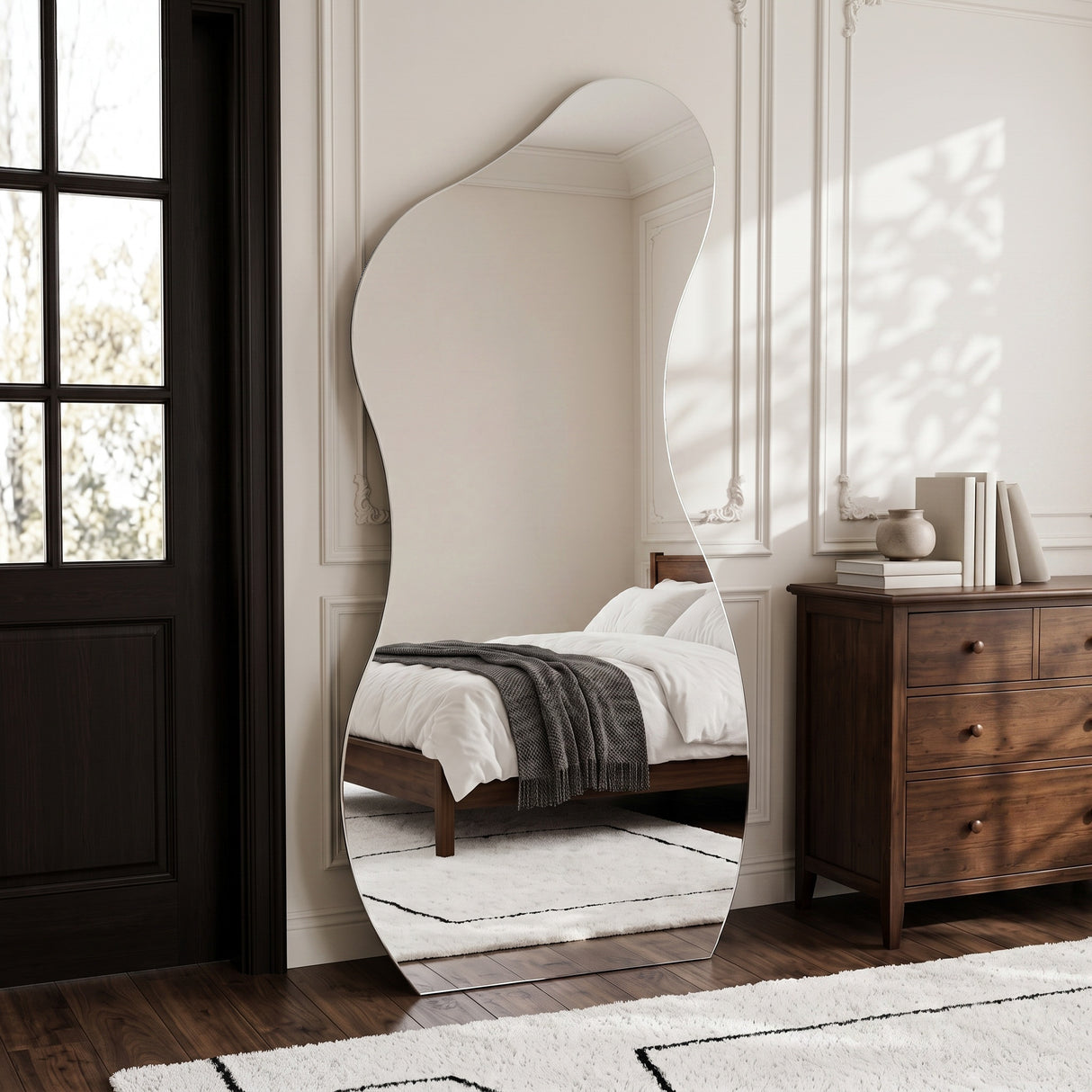 Lesina Frameless Full Length Pond Mirror styled in a bedroom beside a wooden chest of drawers.