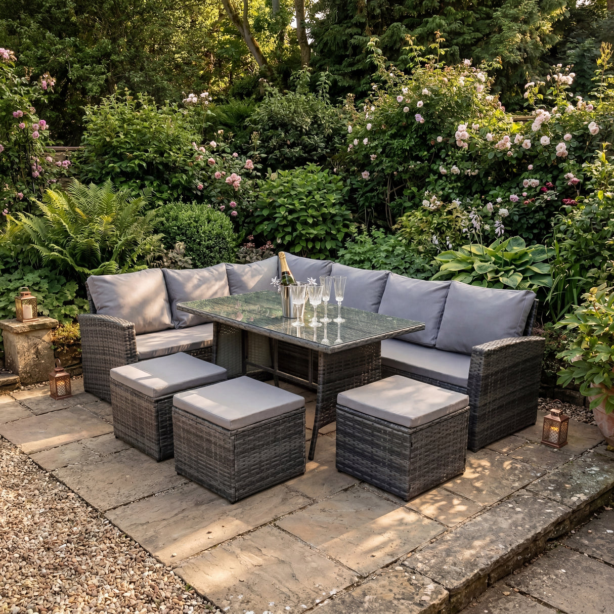 Outdoor patio set with table and chairs on a stone patio surrounded by greenery.