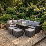 Outdoor patio set with table and chairs on a stone patio surrounded by greenery.