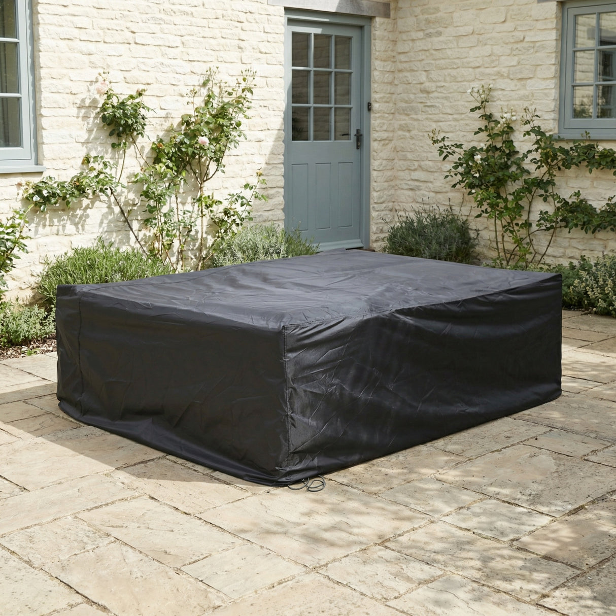 Black outdoor furniture cover on a patio in front of a brick building.
